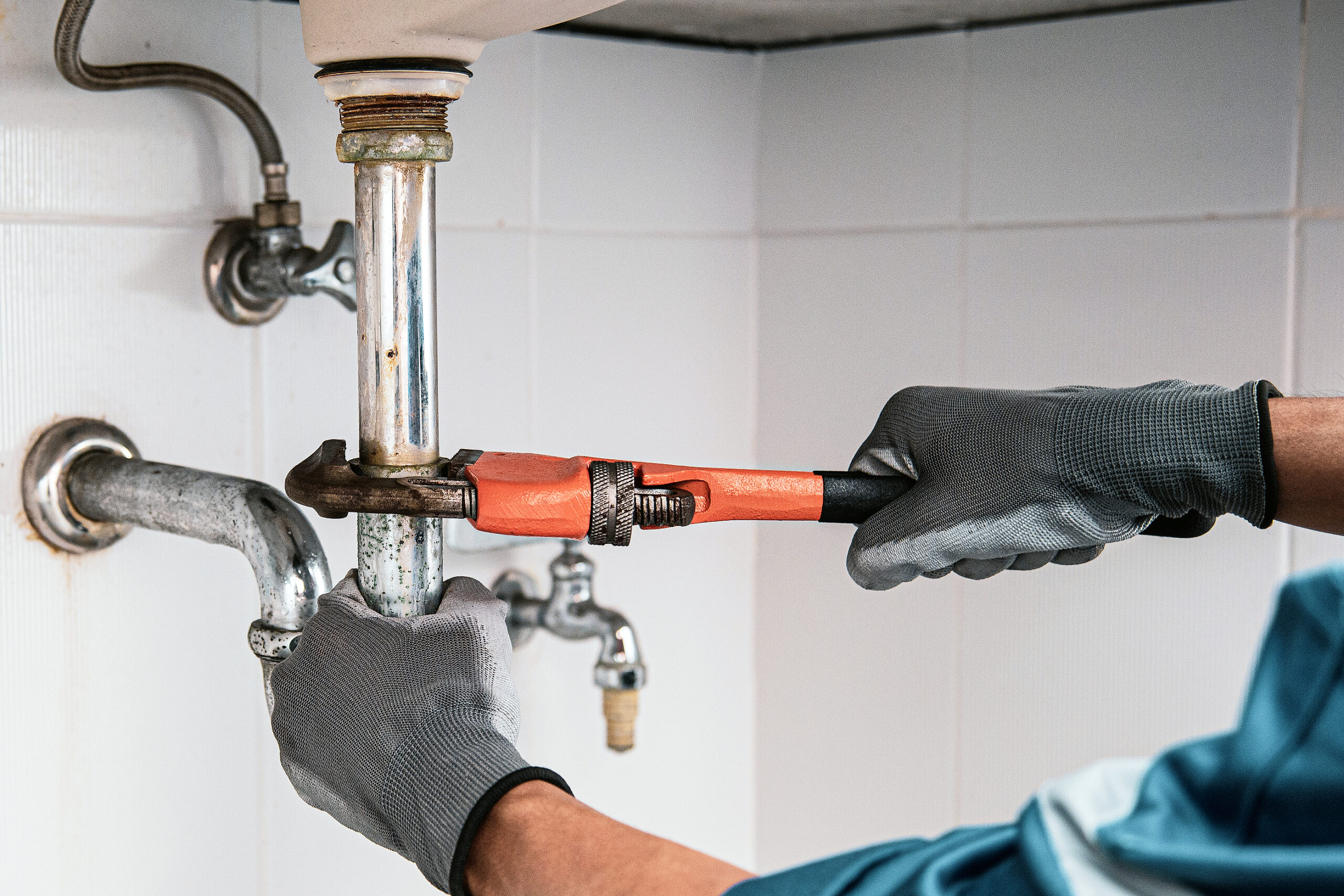 Technician plumber using a wrench to repair a water pipe under the sink. Concept of maintenance, fix water plumbing leaks, replace the kitchen sink drain, cleaning clogged pipes is dirty or rusty.